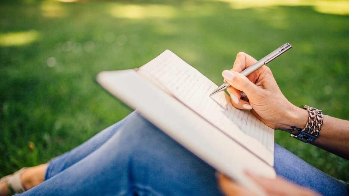 woman writing a letter outside in the grass