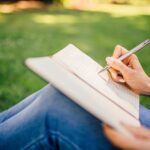 woman writing a letter outside in the grass